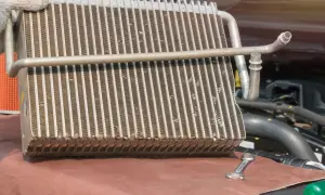 Main d'un mécanicien tenant un radiateur de voiture pour sa réparation. Une clé est posée à côté.