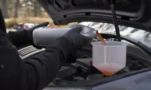 Maintenant, découvrez comment purger le liquide de refroidissement sans vis de purge. On verse le liquide orange dans un entonnoir.