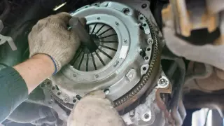 Mécanicien ajustant la butée d'embrayage d'une voiture avec un outil.
