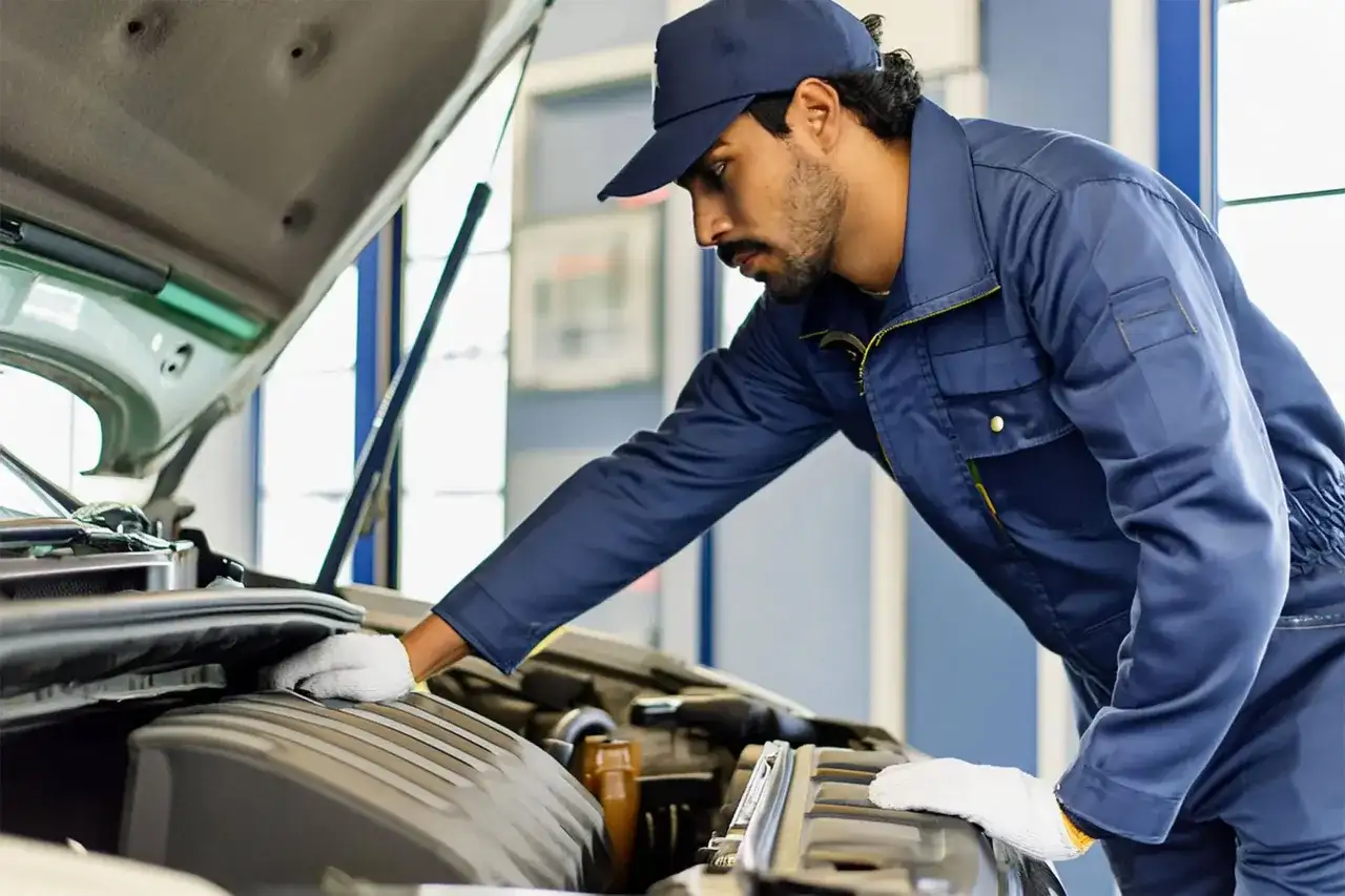 Mécanicien en bleu, casquette, gants blancs, travaillant sur le moteur. Il s'occupe de nettoyer injecteur qui claque pour une meilleure performance.