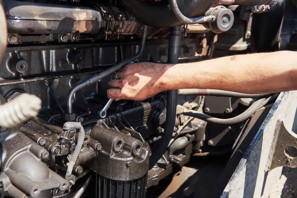 Main d'un mécanicien travaillant sur un moteur diesel, essentiel pour sa durée de vie.