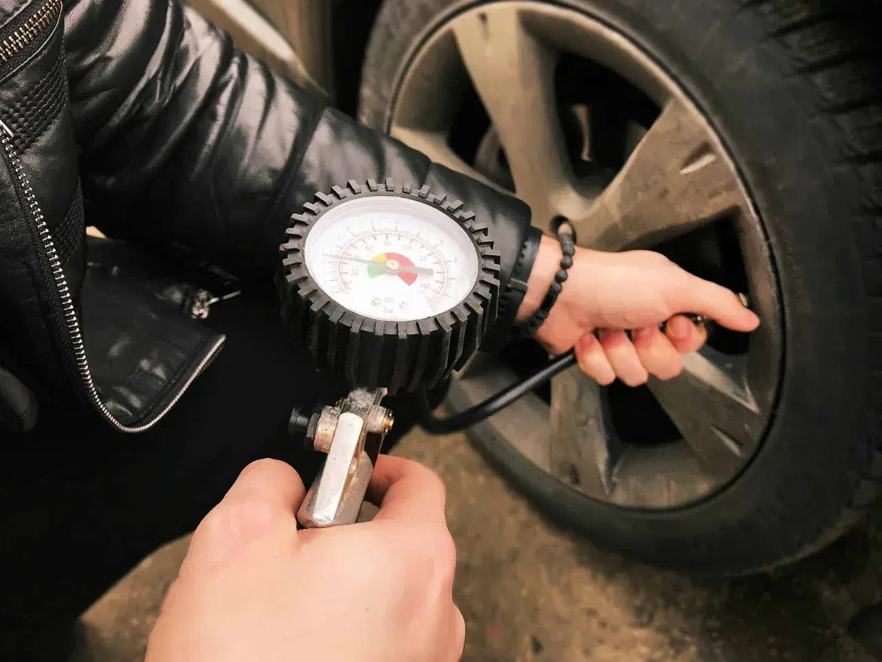 Main tenant une tpw a controler, vérifie la pression des pneus d'une voiture.
