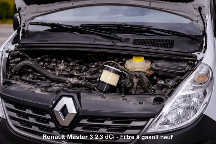 Moteur de Renault Master 3 2.3 dCi ouvert, montrant le **changement filtre à gasoil** en cours. Le nouveau filtre est visible.